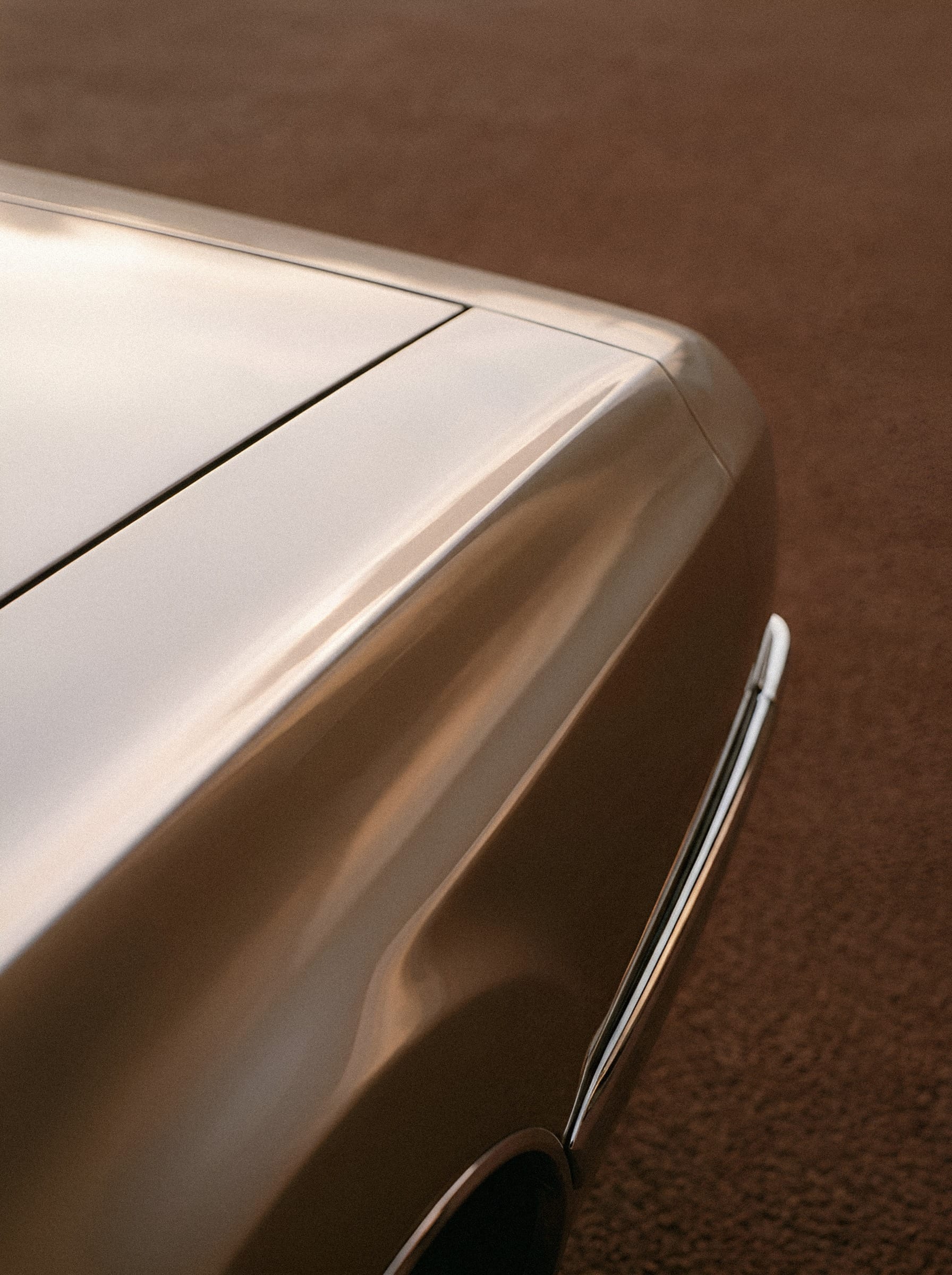 A close view of a cream car panel with a dark seam and a long strip of chrome trim.