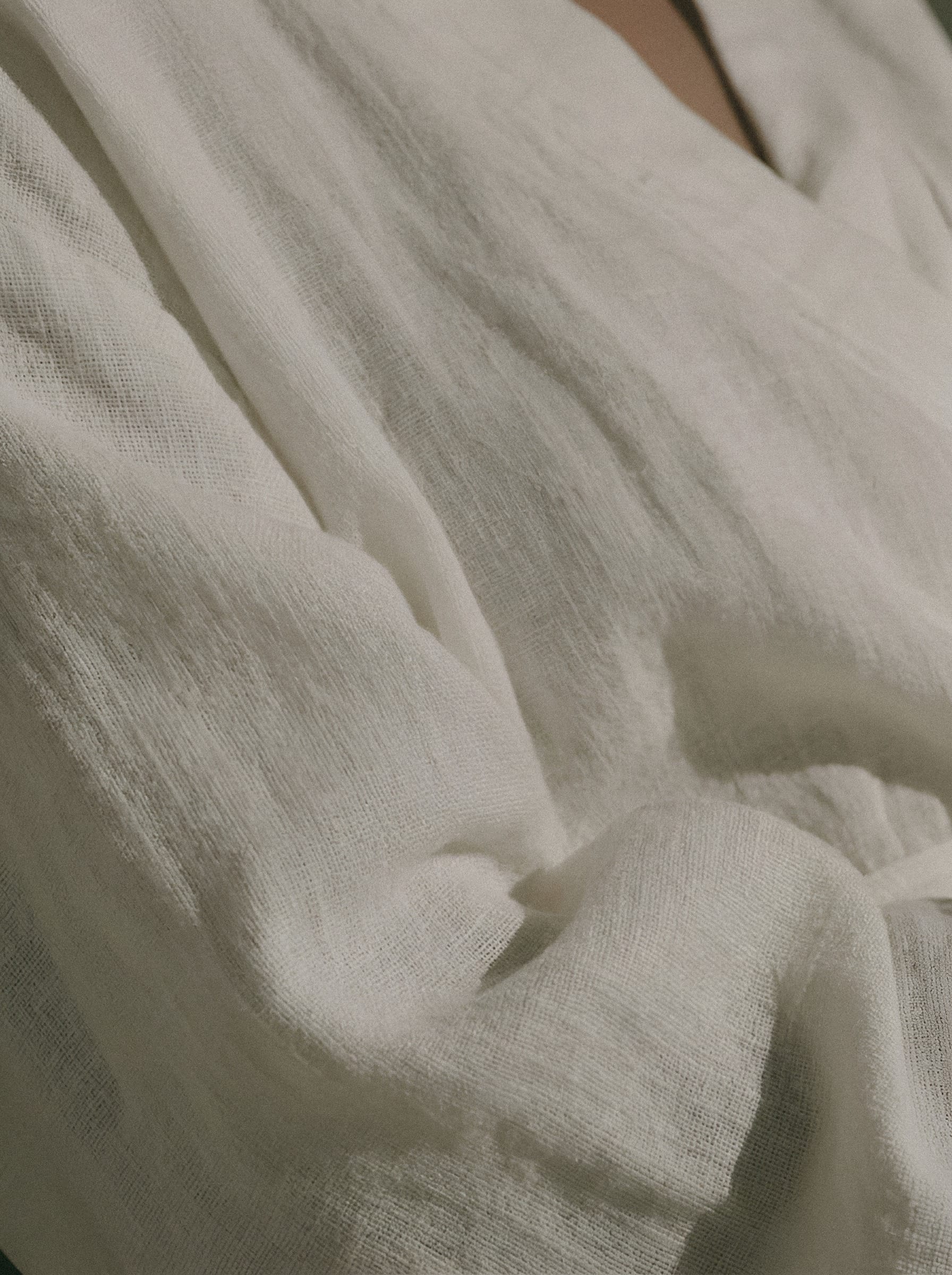 Cream linen gathered into soft folds in side light.