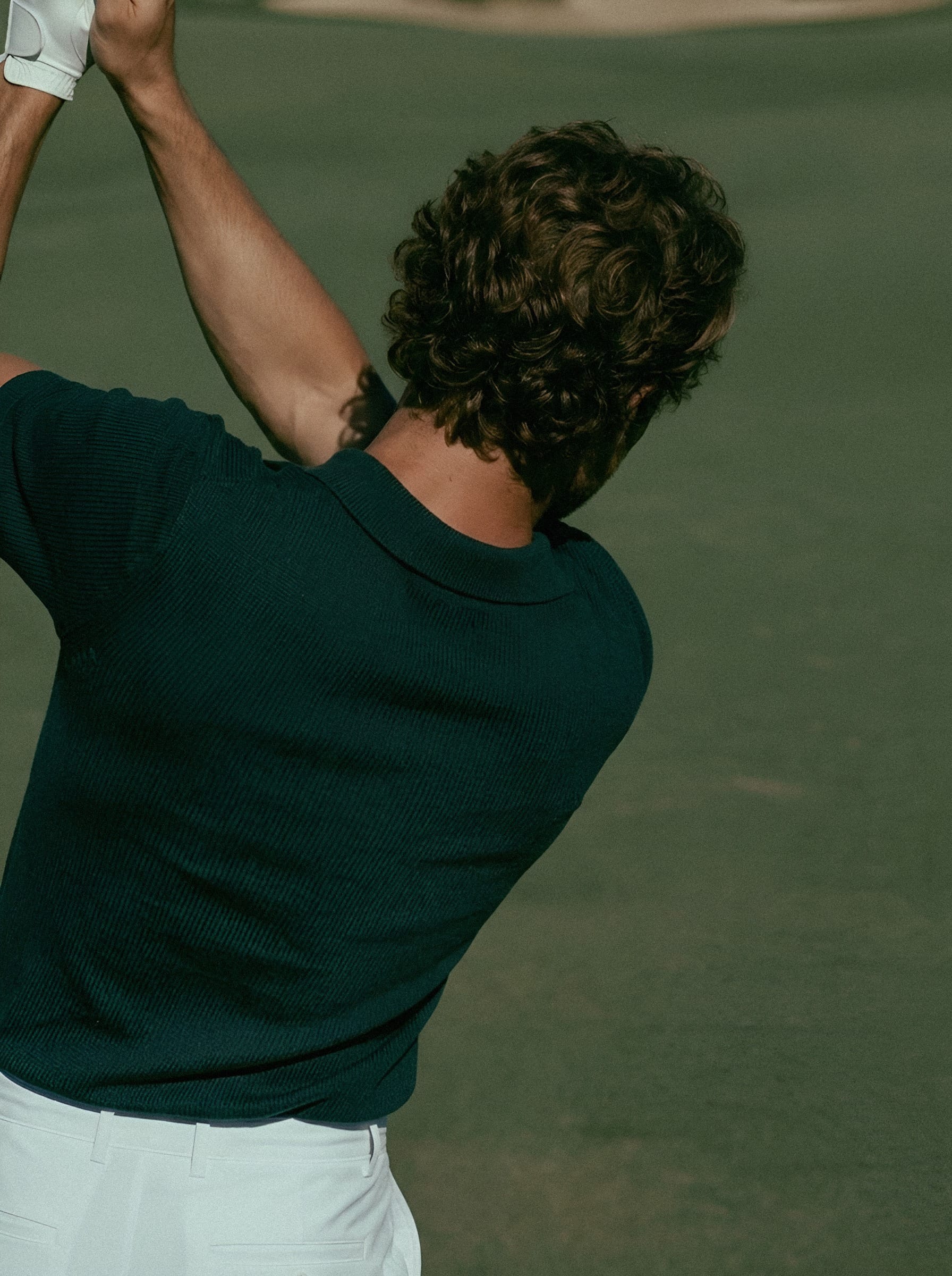 A golfer holding a club above his shoulder after a swing.