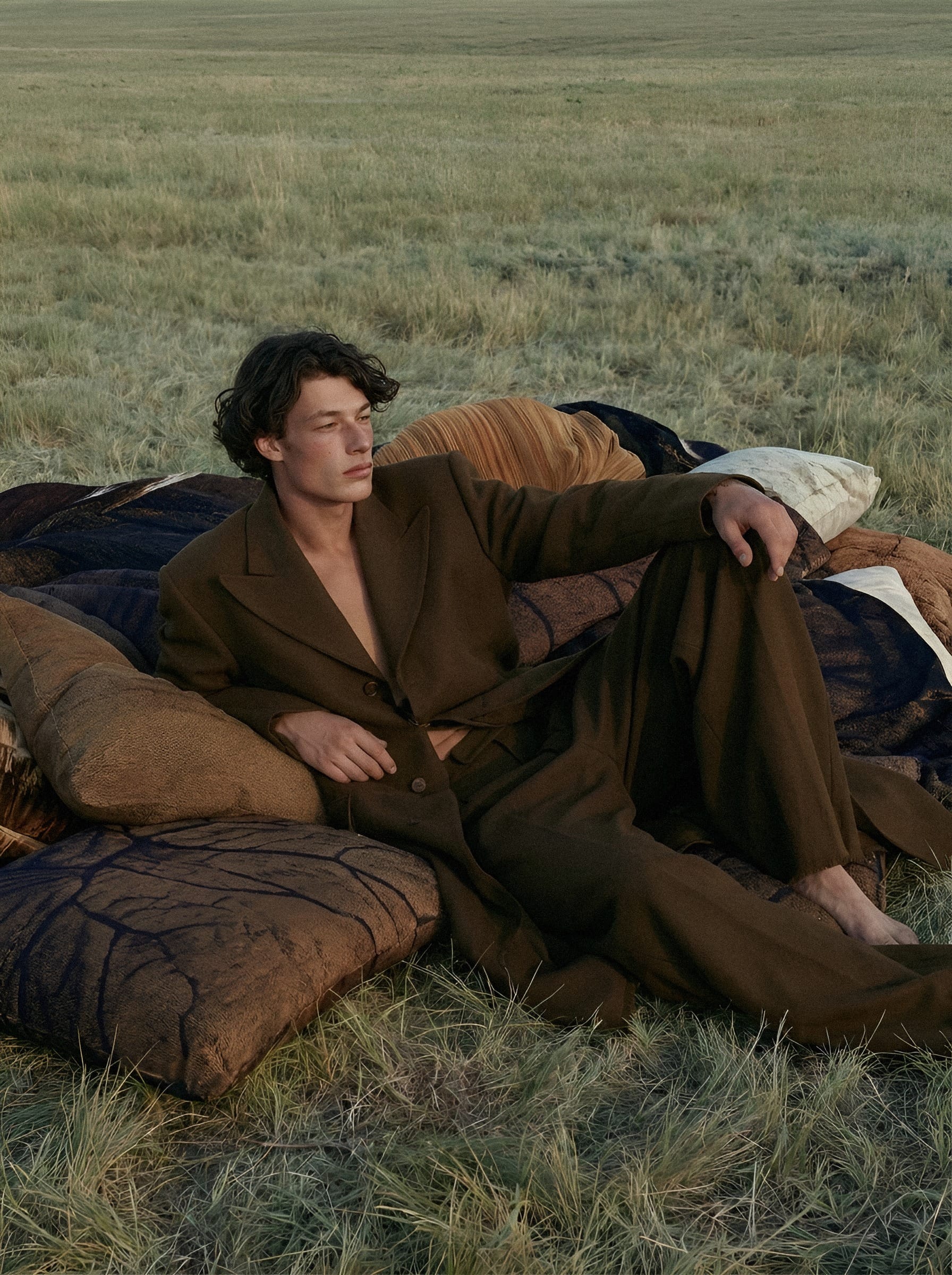 Man resting on bedding in grassland.