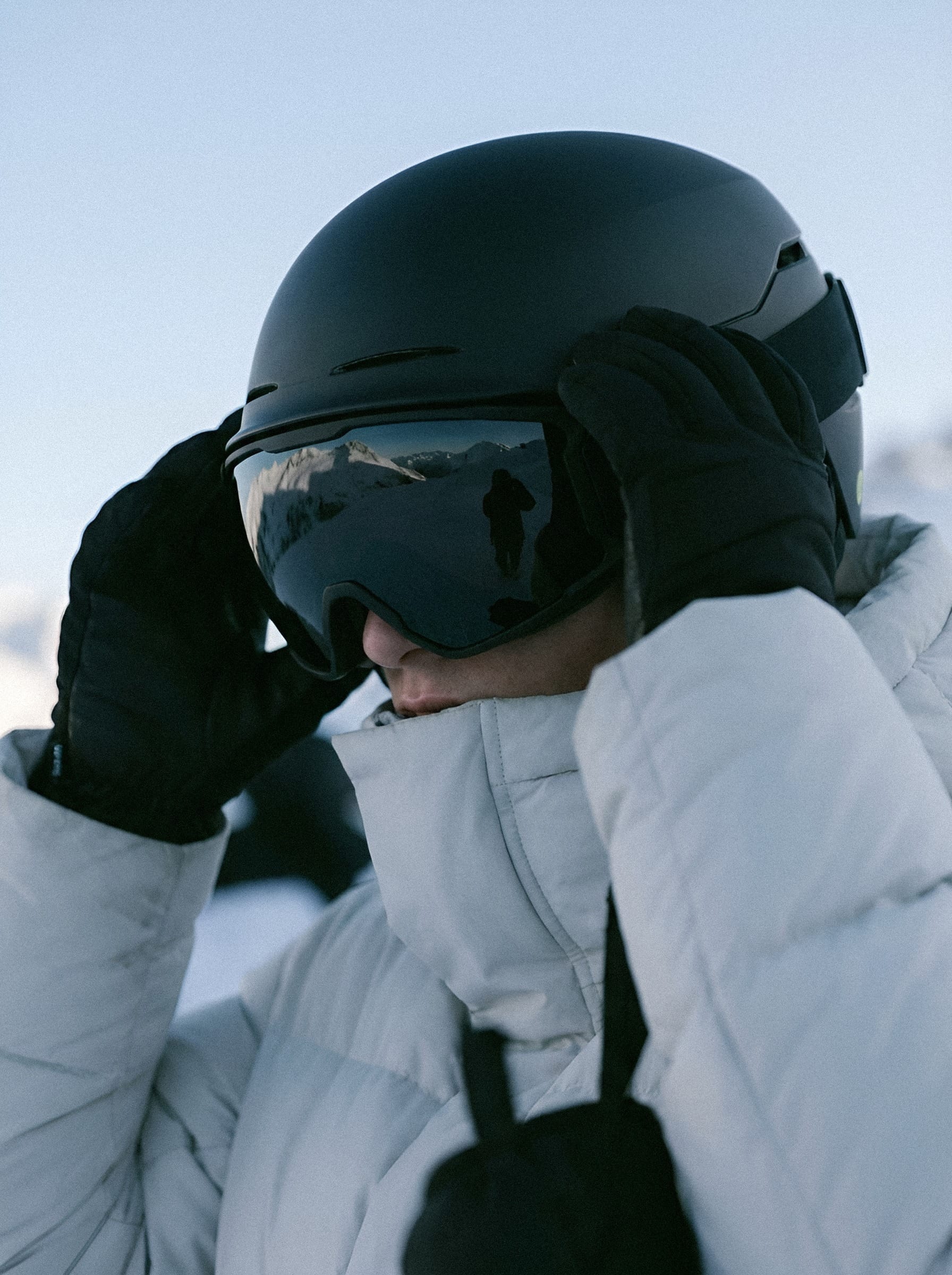 Skier adjusting goggles on slope.