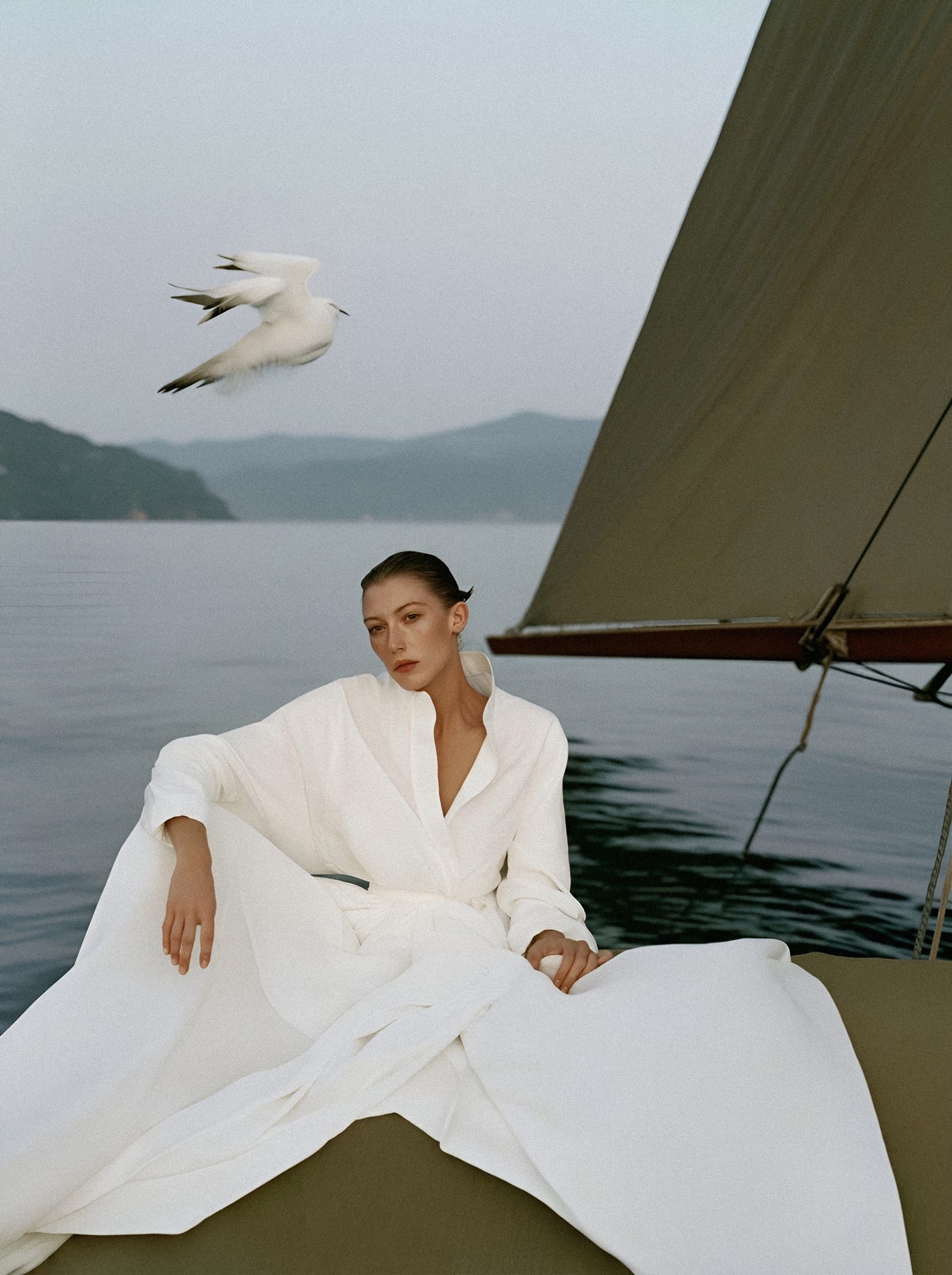 Woman in white linen on moored sailboat.