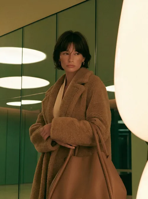 Woman in camel coat interior light.
