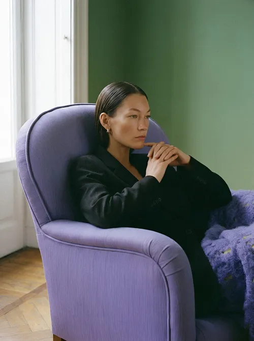 Woman in lavender chair considering.