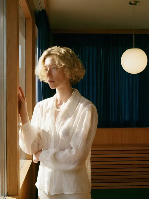 Woman in white shirt by window.